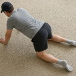 Homme à quatre pattes sur une moquette, vu de dos, en position de départ d'un exercice de renforcement du dos